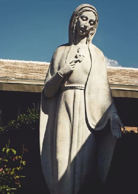 Una estatua de María en un jardín.